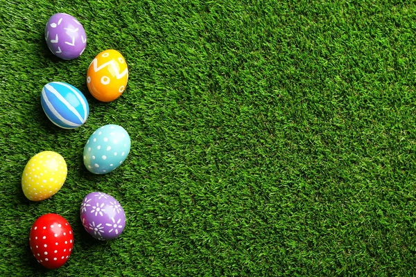 Composición plana de los huevos de Pascua pintados sobre hierba verde, espacio para el texto —  Fotos de Stock