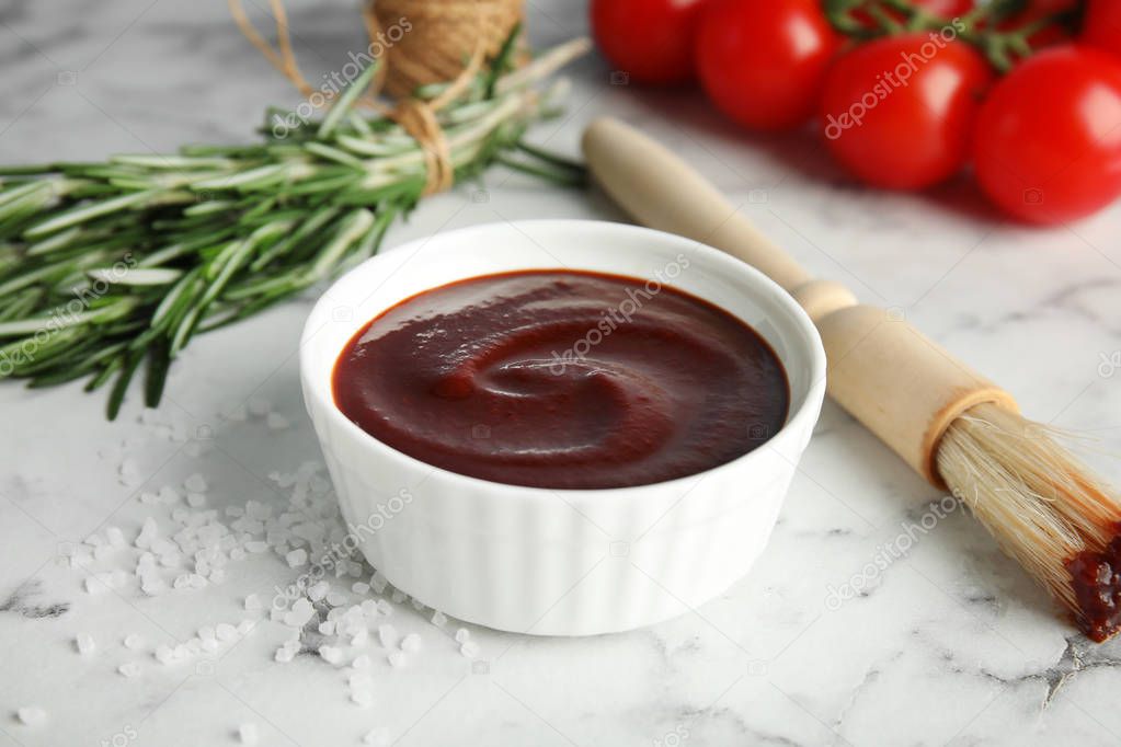 Composition with bowl of barbecue sauce on marble background