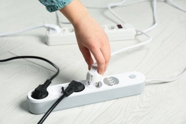 Bir kadın yerden uzatma kablosuna güç takıyor, yakın plan. Elektrikçinin profesyonel ekipmanı