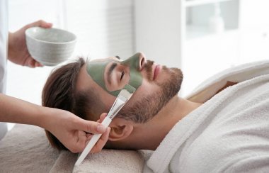 Spa salonu müşterinin yüzüne maske uygulayarak güzellik uzmanı