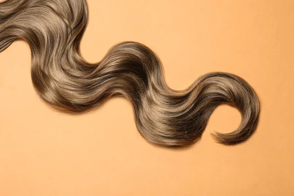 Mechón de pelo castaño ondulado sobre fondo de color, vista superior — Foto de Stock