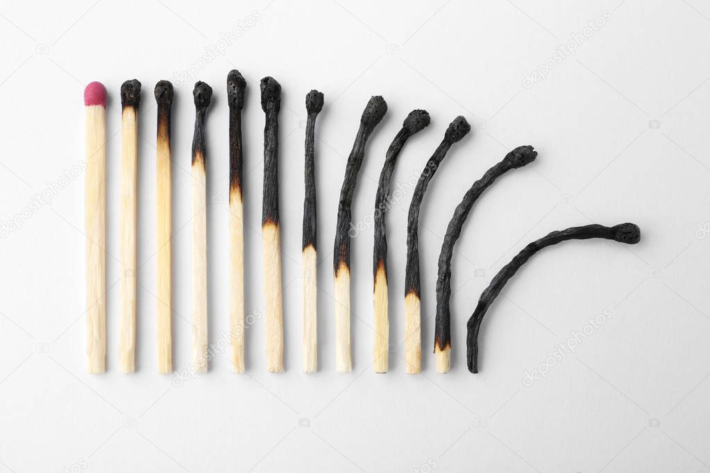 Row of burnt matches and whole one on white background, top view. Human life phases concept