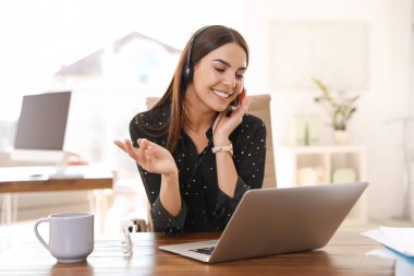 Merkez ofisteki bilgisayarda görüntülü konuşma yapan genç bir kadın.