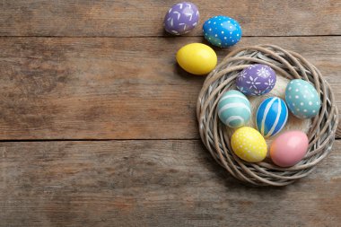 Hasır yuva ile ahşap masa, üstten görünüm üzerinde Paskalya yumurta boyalı. Metin için yer