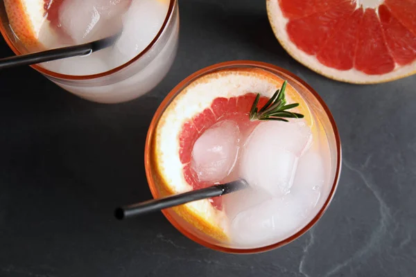 Vasos de cóctel y rodaja de pomelo en la mesa oscura, puesta plana —  Fotos de Stock