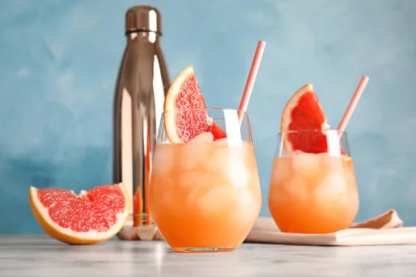 Стаканы грейпфрутовых коктейлей подаются на столе на цветном фоне — стоковое фото