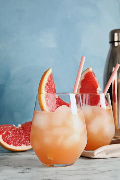 Стаканы грейпфрутовых коктейлей подаются на столе на цветном фоне. Пространство для текста — стоковое фото
