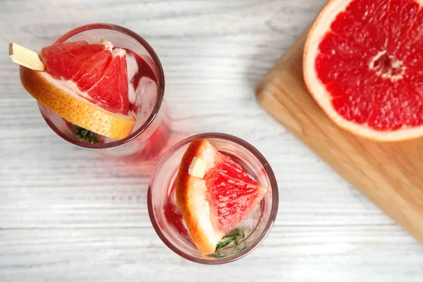 Composición laica plana con vasos de cócteles de pomelo sobre mesa de madera — Foto de Stock