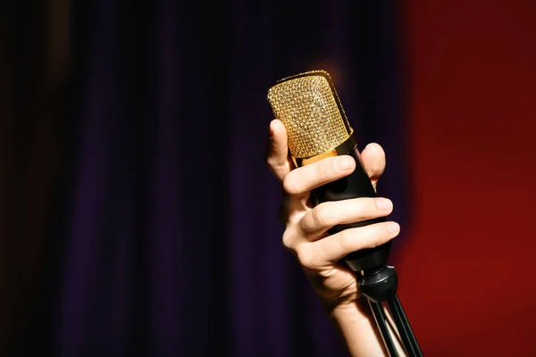 Женщина держит микрофон на цветном фоне, крупным планом. Пространство для текста — стоковое фото