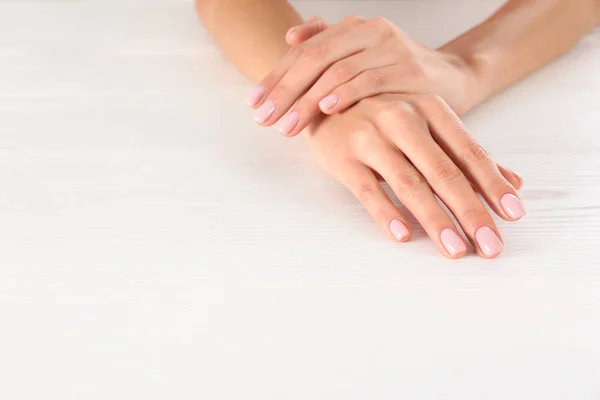 Vista de cerca de la mujer con hermosas manos en la mesa de madera blanca, espacio para el texto. Tratamiento de spa — Foto de Stock