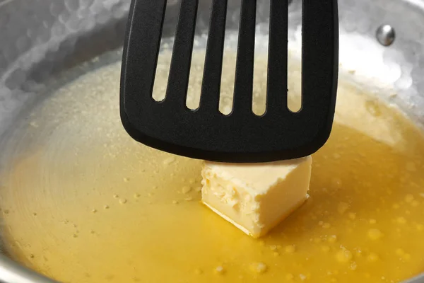 Сковородка с плавильным маслом и лопаткой, крупным планом — стоковое фото