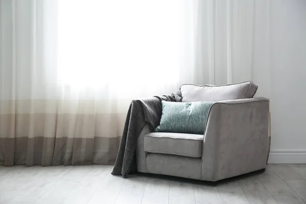 Acogedor sillón con almohadas y cuadros cerca de la ventana en la habitación. Diseño de interiores — Foto de Stock
