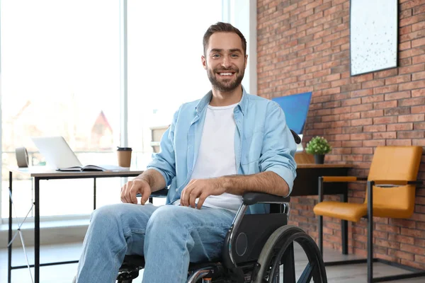 Portret van een jonge man in rolstoel op kantoor — Stockfoto