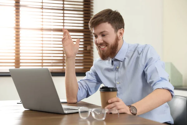 Homem usando chat de vídeo no laptop no escritório em casa — Fotografia de Stock