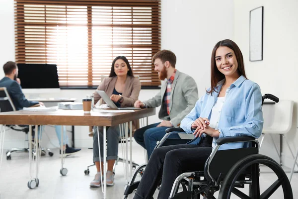 Młoda kobieta na wózku inwalidzkim z kolegami w biurze — Zdjęcie stockowe