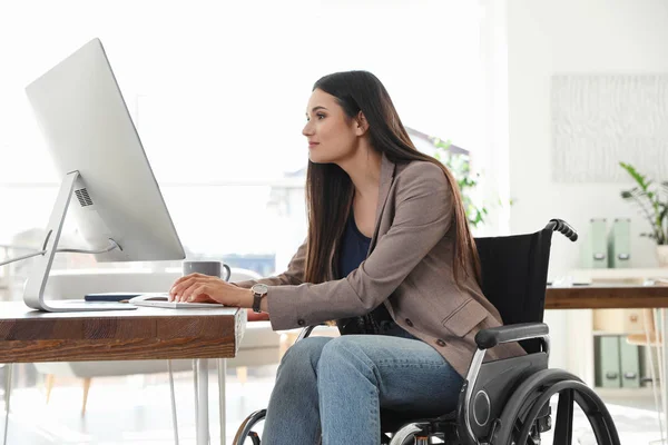 Junge Frau im Rollstuhl nutzt Computer am Arbeitsplatz — Stockfoto