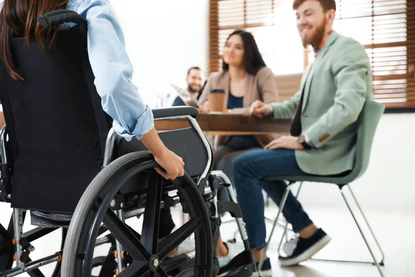 Młoda kobieta na wózku inwalidzkim z kolegami w biurze, zbliżenie — Zdjęcie stockowe