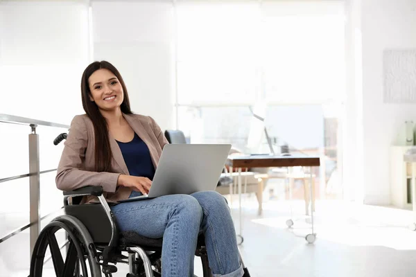 Retrato de mujer joven en silla de ruedas con portátil en la oficina —  Fotos de Stock