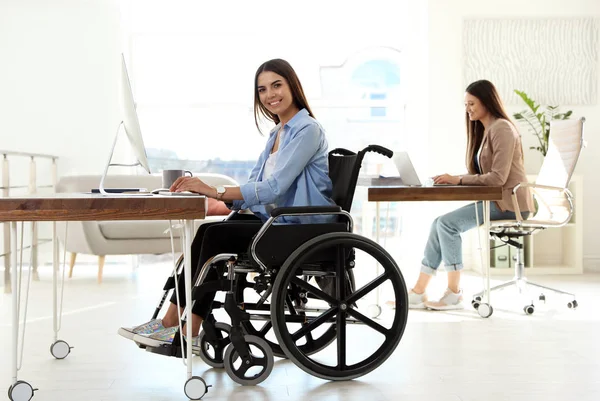 Jonge vrouw in rolstoel met behulp van computer op het werk — Stockfoto