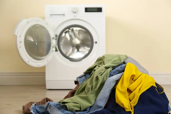 Montón de ropa sucia cerca de la lavadora en interiores — Foto de Stock