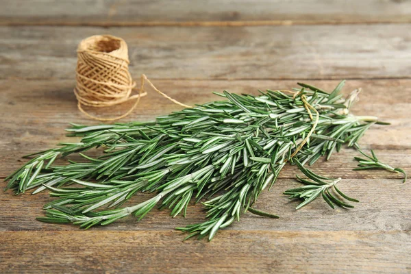 Fresh rosemary branches and twine on wooden table — Stock Photo, Image