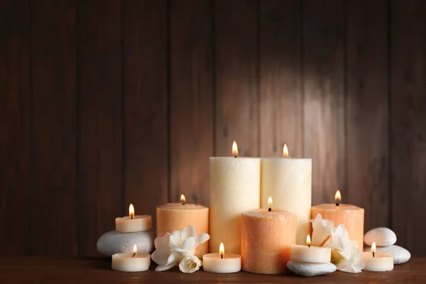Hermosa composición con velas, flores y piedras sobre la mesa sobre fondo de madera. Espacio para texto — Foto de Stock