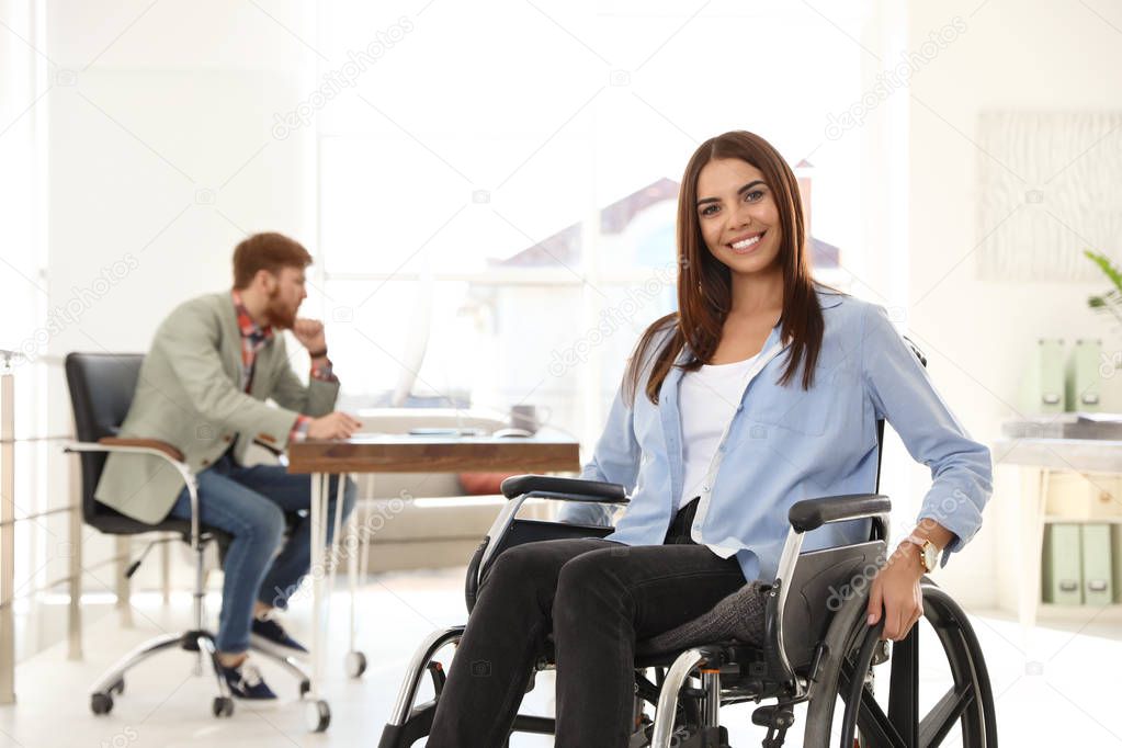 Young woman in wheelchair with colleague at office