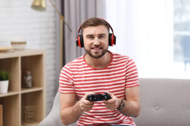 Genç adam evde video oyunu oynuyor.