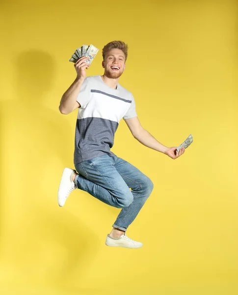 Молодий чоловік стрибає з грошима на кольоровому фоні — стокове фото