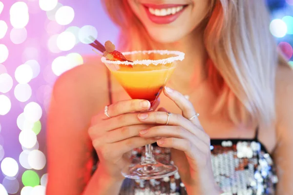 Młoda kobieta ze szklanką koktajlu martini przed świątecznymi światłami, zbliżenie — Zdjęcie stockowe