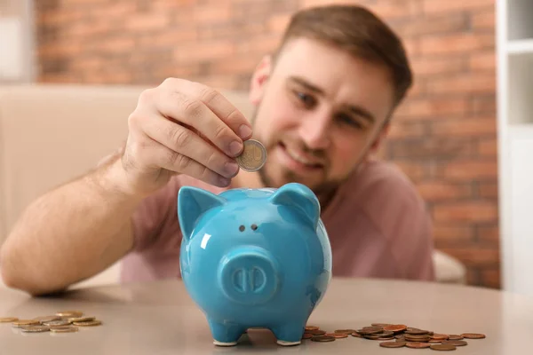Fiatal férfi malacpersellyel és pénzzel otthon, közelkép — Stock Fotó