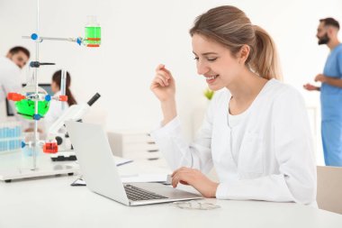 Modern laboratuvarda dizüstü bilgisayar ile çalışan tıbbi öğrenci