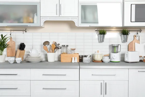 Mutfak tezgahında farklı aletler, temiz bulaşıklar ve mutfak eşyaları — Stok fotoğraf