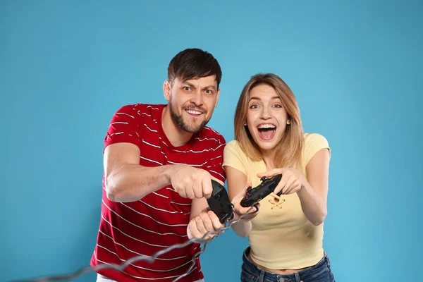 Емоційна пара грає у відеоігри з контролерами на кольоровому фоні — стокове фото