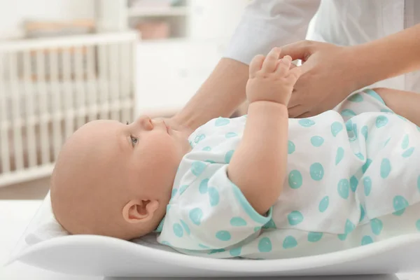 Läkare viktning baby på skalor i ljust rum — Stockfoto