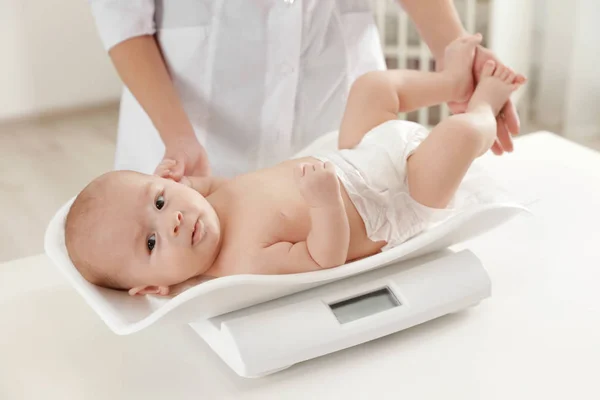 Arzt wägt Baby auf Waage im hellen Raum — Stockfoto