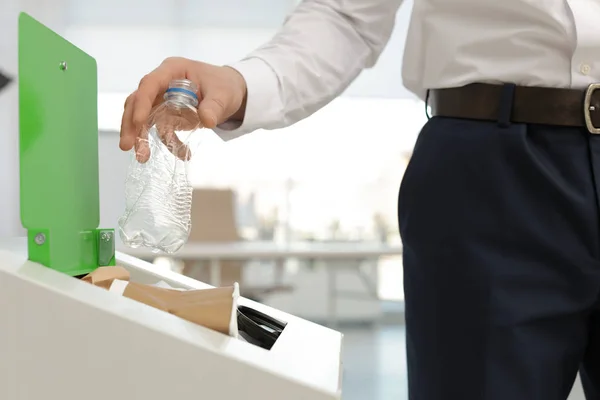 Hombre poniendo botella de plástico usado en la papelera en la oficina, primer plano. Reciclaje de residuos —  Fotos de Stock