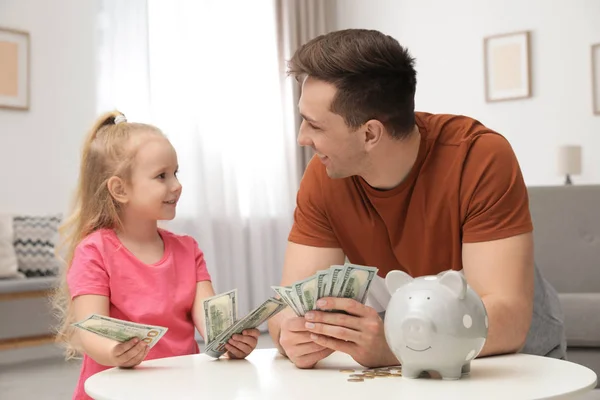 Vader en dochter tellen geld aan tafel binnenshuis — Stockfoto