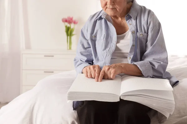 Niewidoma osoba Starsza czytanie książka napisana w alfabecie Braille'a na łóżku w pomieszczeniu, zbliżenie. Miejsce na tekst — Zdjęcie stockowe