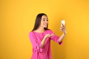 Renkli arka planda görüntülü sohbet için cep telefonu kullanan kadın