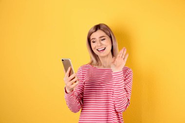 Renkli arka planda görüntülü sohbet için cep telefonu kullanan kadın