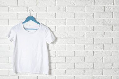 Tuğla duvara karşı beyaz tişörtlü askı. Tasarım için mockup