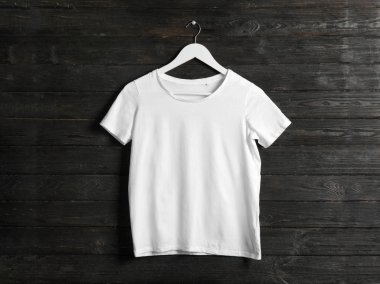 Ahşap arka planda beyaz tişörtlü askı. Tasarım için mockup