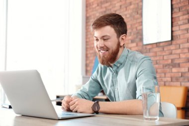 Genç adam evdeki bilgisayarında görüntülü konuşma yapıyor.