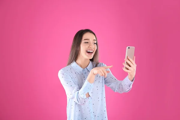 Femme utilisant un téléphone mobile pour le chat vidéo sur fond couleur — Photo
