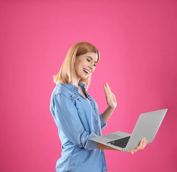 Женщина использует ноутбук для видео чата на цветном фоне — стоковое фото