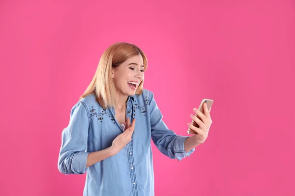 Mulher usando telefone celular para bate-papo de vídeo em fundo de cor — Fotografia de Stock