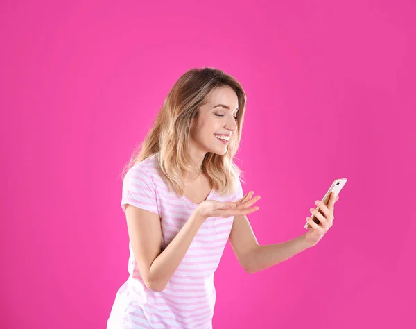 Mulher usando telefone celular para bate-papo de vídeo em fundo de cor — Fotografia de Stock