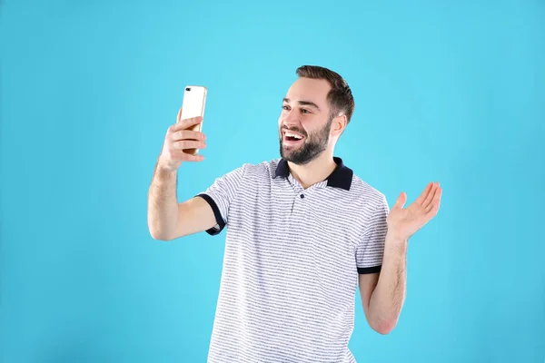 色の背景にビデオチャットのために携帯電話を使用している男 — ストック写真