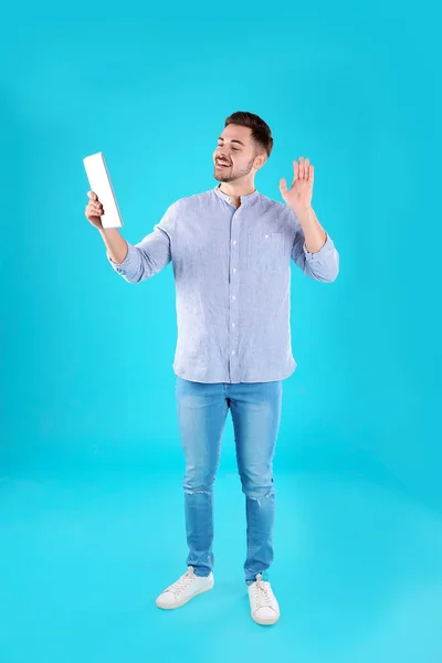 Homem usando tablet para bate-papo por vídeo em fundo de cor — Fotografia de Stock